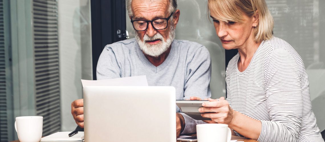 Senior couple reading documents and calculating bills to pay in living room at home.Retirement couple and loan bankruptcy money concept